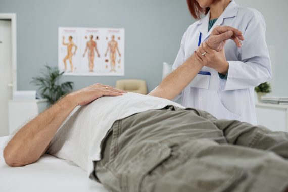 Chiropractor examining senior man in her office